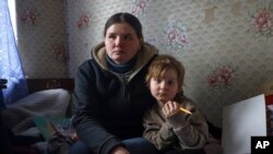 A woman from Soledar and her child sit inside a temporary accommodation somewhere near Shakhtarsk, in Russian-controlled Donetsk region, eastern Ukraine, Jan. 13, 2023.