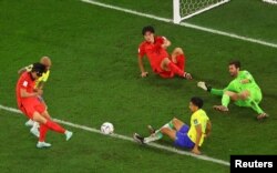 Jwe Sid Koreyen Son Heung-min choute balon an nan direksyon gol la pandan ko-ekipye li Cho Gue-sung ak Brezilyen Marquinhos ak Alisson reyaji, 5 Desanm, 2022.