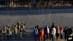 Anggota pasukan militer AS memberhentikan migran untuk tidak menyeberang ke wilayah El Paso, Texas, dari Ciudad Juarez, Meksiko, pada 20 Desember 2022. (Foto: AP/Christian Chavez)