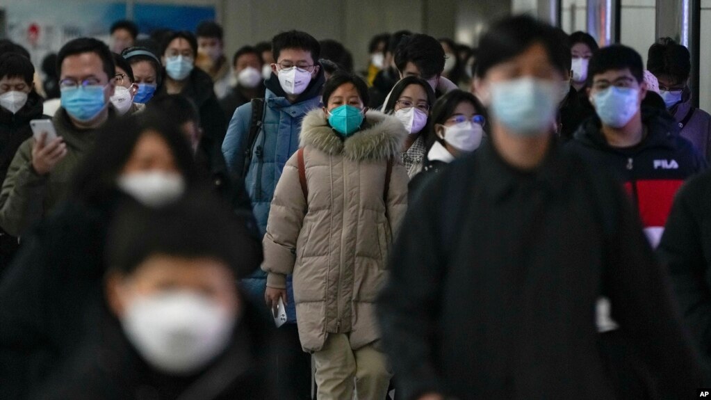 资料照 - 2022年12月20日的北京街头，带口罩的通勤者在交通高峰期匆忙赶去上班。在突然放开了执行将近3年的严格封控政策后，中国多地新冠感染病例暴增，并且出现了奥密克戎病毒的变异毒株。(photo:VOA)