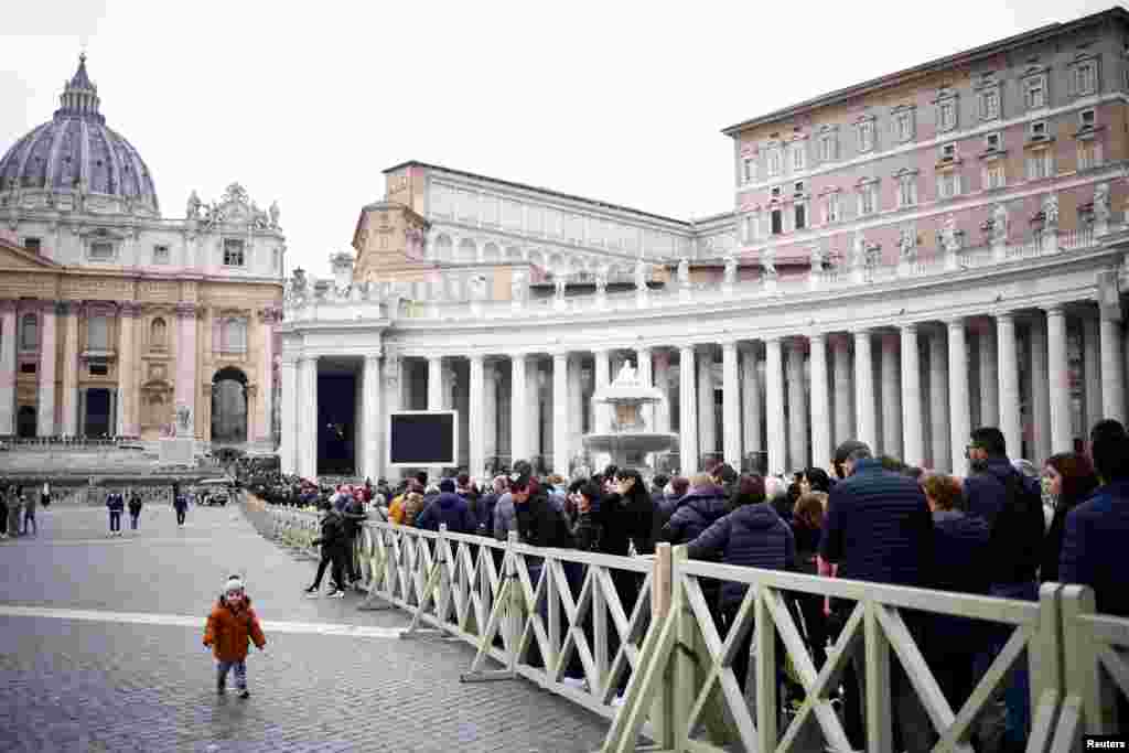 Un niño camina afuera de la Basílica de San Pedro mientras fieles hacen cola para rendir homenaje al fallecido Benedicto XVI.&nbsp;