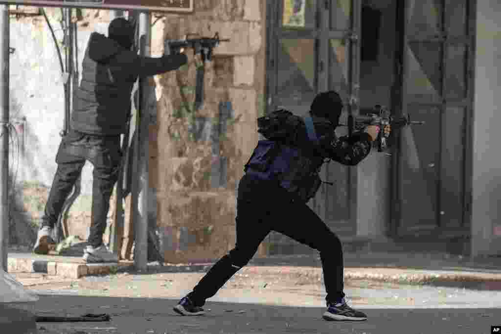 Masked Palestinian gunmen fire during clashes with Israeli security forces in the West Bank city of Nablus.