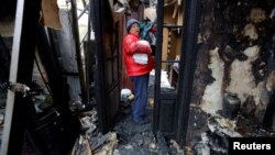 A woman gathers the belongings of her neighbor, who was killed in recent shelling, from a house destroyed in the course of Russia-Ukraine conflict in Donetsk, Russian-controlled Ukraine, Dec. 10, 2022. 