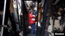 一名妇女在乌克兰顿涅茨克地区被俄罗斯攻击摧毁的住宅中取出衣服（2022年12月10日）