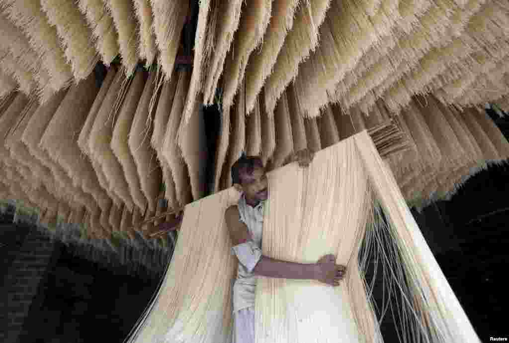 Um homem carrega fios de vermicelli, uma especialidade que se consome durante o mês sagrado do Ramadão pelos muçulmanos. Os vermicelli vão ser secados numa fábrica em Lahore, Paquistão, 6 de Julho, 2015.&nbsp;