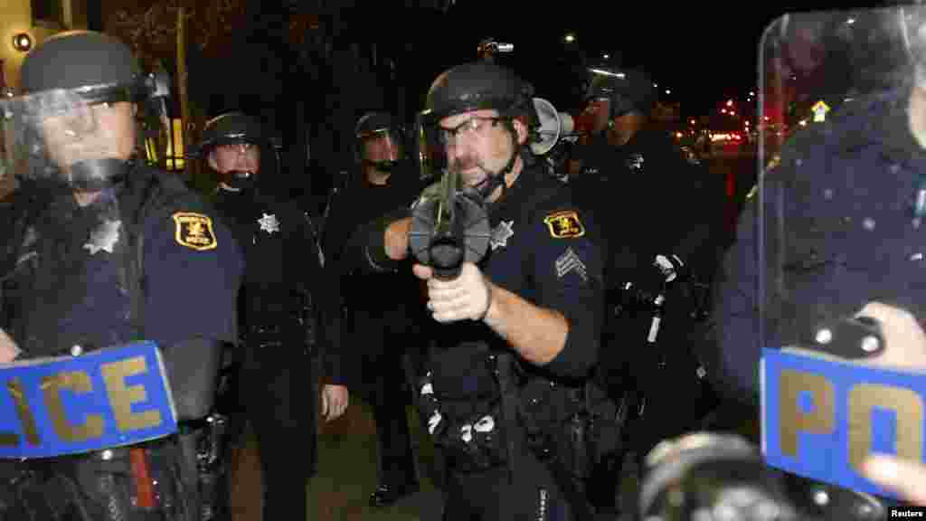 Um polícia enverga a sua arma em direcção a manifestantes durante a marcha contra a decisão do Grande Júri de Nova Iorque em não indiciar criminalmente os polícias envolvidos na morte de Eric&nbsp; Garner. Berkeley, Califórnia, Dec. 8, 2014.