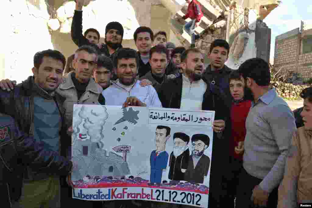Demonstrators hold a placard depicting Syria&#39;s President Bashar al-Assad (L-R), Iran&#39;s Supreme Leader Ayatollah Ali Khamenei and Hezbollah leader Sayyed Hassan Nasrallah during a protest against Assad, after Friday prayers in Kafranbel, near Idlib, December 21.