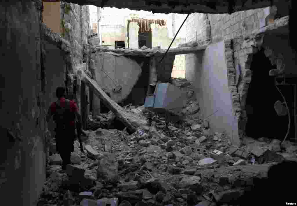 A Free Syrian Army fighter carries his weapon as he walks amongst rubble near Nairab military airport in Aleppo, Syria, June 12, 2013.