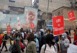FILE - Protesters hold placards during a demonstration against police killings and brutality, in the Mathare slum in Nairobi, Kenya, June 8, 2020.