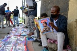 FILE - Ethiopians read newspapers and magazines reporting on the current military confrontation in the country, one of which shows a photograph of Prime Minister Abiy Ahmed, on a street in the capital Addis Ababa, Ethiopia, Nov. 7, 2020.