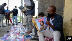 FILE - Ethiopians read newspapers and magazines reporting on the current military confrontation in the country, one of which shows a photograph of Prime Minister Abiy Ahmed, on a street in the capital, Addis Ababa, Nov. 7, 2020.