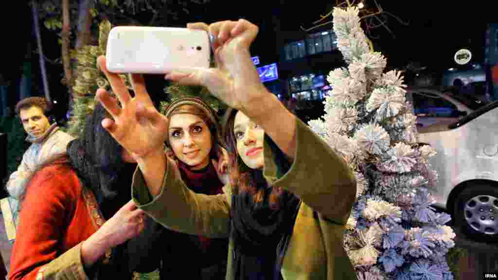 چند خانم جوان ایرانی در تهران، در کنار یک درخت کریسمس، عکس یادگاری می گیرند. عکس: عبدالله حیدری، ایرنا
