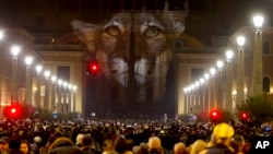 FILE - People gather to watch images projected on the facade of St. Peter's Basilica, at the Vatican, Dec. 8, 2015. Police say they have seized 3,500 fake Vatican parchments that were being sold to unsuspecting pilgrims taking part in Pope Francis' Holy Year celebrations.
