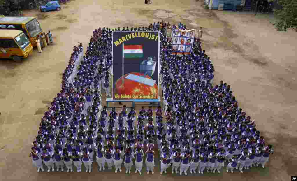 Indian school children pose for photographs with a poster of Mars Orbiter Mission satellite as they celebrate its success in Chennai, India, Sept. 24, 2014.