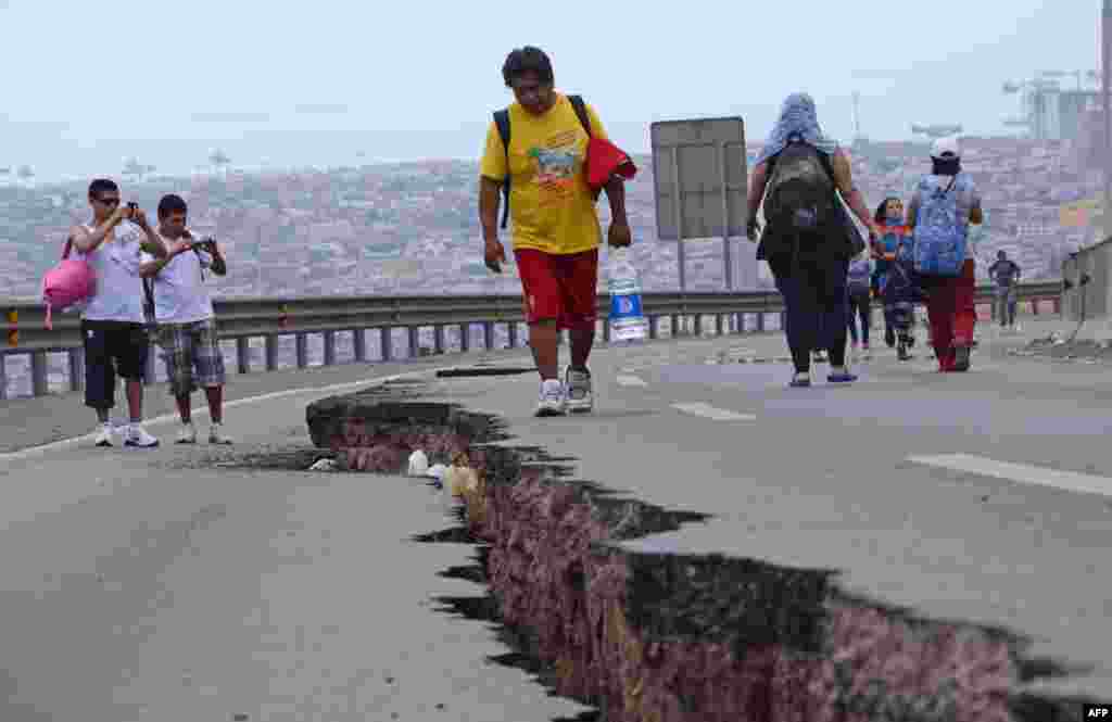 Người dân đi trên con đường bị rạn nứt ở Iquique, bắc Chile, một ngày sau khi một trận động đất&nbsp; 8,2 độ richter làm rung chuyển vùng duyên hải Thái Bình Dương của Chile, ngày 2 tháng 4, 2014.