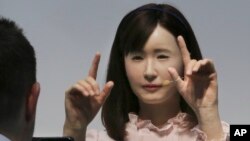 FILE - A prototype of Japanese electronics company Toshiba's female android Ms. Aiko Chihira performs sign language to a visitor during the annual CEATEC Japan advanced technologies show.
