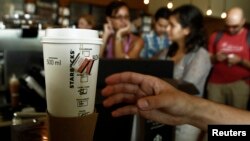 FILE - A customer reaches out for a Starbucks beverage at the new Starbucks coffee store in San Jose, Costa Rica, June 20, 2012. 