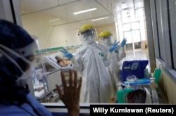 Isyarat petugas kesehatan yang mengenakan APD di ruang isolasi pasien COVID-19 usai pengambilan sampel usap, di IGD RS Persahabatan, Jakarta, 13 Mei 2020. (Foto: REUTERS/Willy Kurniawan)