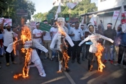 Activists burn effigies depicting India's Home Minister Amit Shah, Prime Minister Narendra Modi and Chief Minister of Assam Sarbananda Sonowal, during a protest against the Citizenship Amendment Bill, in Guwahati, India, Dec. 4, 2019.