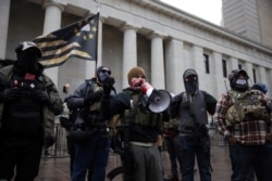 Miembros de milicias armadas se reúnen para proteger a los manifestantes mientras los partidarios del presidente de Estados Unidos, Donald Trump, protestan contra la elección del presidente electo Joe Biden, frente al Capitolio del estado de Ohio, EE.UU., el 17 de enero de 2021.