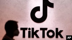 FILE:- A visitor passes the TikTok exhibition in Cologne, Germany, Aug. 25, 2022. The European Union's digital policy chief has warned that the social media app will have to fall in line with tough new rules for online platforms set to take effect later this year. 