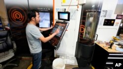 FILE - A worker at Reata Engineering and Machine Works programs a Mazak Variaxis machine used to make semiconductor pieces on Feb. 15, 2024, in Englewood, Colorado. A U.S. employment report released on June 7, 2024, showed continued strength in added jobs.