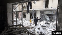 A woman walks through rubble from a building destroyed by shelling from forces loyal to Syrian President Bashar Al-Assad in downtown Aleppo August 1, 2012.