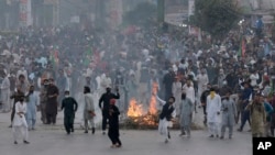 Supporters of former Pakistani Prime Minister Imran Khan's party, Pakistan Tehreek-e-Insaf, throw stones toward police officers during a protest to condemn a shooting incident on their leader's convoy, in Rawalpindi, Pakistan, Friday, Nov. 4, 2022.