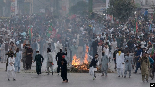 Supporters of former Pakistani Prime Minister Imran Khan's party, Pakistan Tehreek-e-Insaf, throw stones toward police officers during a protest to condemn a shooting incident on their leader's convoy, in Rawalpindi, Pakistan, Friday, Nov. 4, 2022.