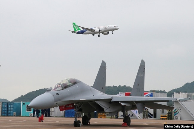 珠海航空展上展示的C-919远航大型客机在一架中国空军战机上空飞过。（2022年11月8日）