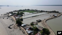 Boats sit near homes in the Sundarbans, the world’s largest mangrove forest, near the Maitree Super Thermal Power Project in Rampal, Bangladesh, Tuesday, Oct. 18, 2022.