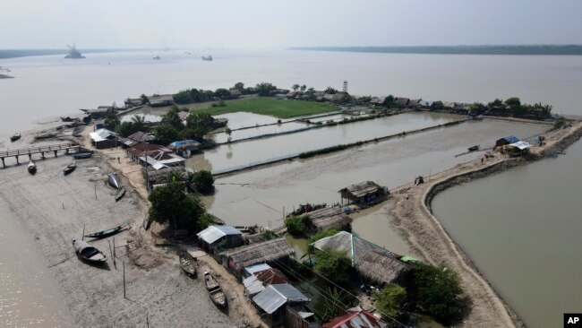 Boats sit near homes in the Sundarbans, the world’s largest mangrove forest, near the Maitree Super Thermal Power Project in Rampal, Bangladesh, Tuesday, Oct. 18, 2022. (AP Photo/Al-emrun Garjon)