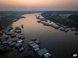A lake in the city of Carauari surrounded by houses is seen during sunrise in Amazonia, Brazil, on Thursday, September 1, 2022. Along the Jurua River, a tributary of the Amazon, riverside settlers and indigenous villages are working together to promote sustainable fishing. Near a magical fish called Pirarucu.  (AP Photo/Jorge Senz)