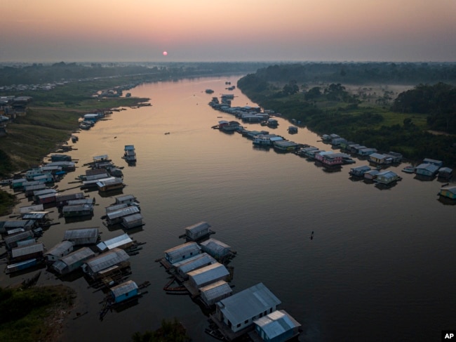 Surrounded by houses the lake in Carauari city is seen during sunrise, Amazonia, Brazil, Thursday, Sept. 1, 2022. Along the Jurua River, a tributary of the Amazon, riverine settlers and Indigenous villages are working together to promote the sustainable fishing of near magic fish called pirarucu. (AP Photo/Jorge Saenz)