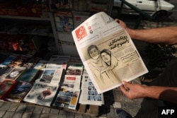 FILE - A man holds a copy of the Hammihan newspaper, in Tehran, Oct. 30, 2022. The article talks of the detention by authorities of two journalists, Niloufar Hamedi and Elaheh Mohammadi (drawing on cover), who according to local media, helped publicize the case of Masha Amini.