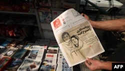 FILE - A man holds a copy of a newspaper in the Iranian capital, Tehran, Oct. 30, 2022, featuring a story on the detention of journalists Niloufar Hamedi and Elaheh Mohammadi (drawing on cover page) who, according to local media, helped publicize the case of Mahsa Amini.