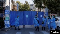 Officials wearing protective aprons stand outside the boarded-up gate of a residential compound that was placed under lockdown as outbreaks of coronavirus disease (COVID-19) continue in Beijing, Nov. 7, 2022. 