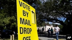 A sign directs voters as people leave an early voting site, Monday, Oct. 31, 2022, in Miami. Midterm elections are Nov. 8. (AP Photo/Lynne Sladky)