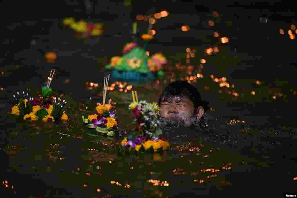 A boy swims in Chao Phraya River as he helps to place a Krathong, or a &quot;floating basket&quot;, in the water during the Loy Kratong festival in Bangkok, Thailand.