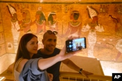 Pengunjung Mesir Ahmed Darwish berfoto selfie dengan teman Ukrainanya Elena, di makam Raja Tutankhamun di Lembah Para Raja di Luxor, Mesir, Jumat, 4 November 2022. (AP/Amr Nabil)