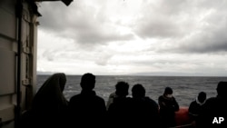FILE - Migrants stand on the deck of the Ocean Viking rescue ship, in the Strait of Sicily, in the Mediterranean Sea, Nov. 5, 2022. 