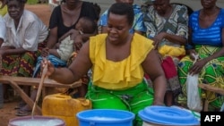 A woman dilutes chlorine as other women wait to receive the concentrate to protect their households from cholera outbreak in Likuni, Malawi, January 27, 2018.