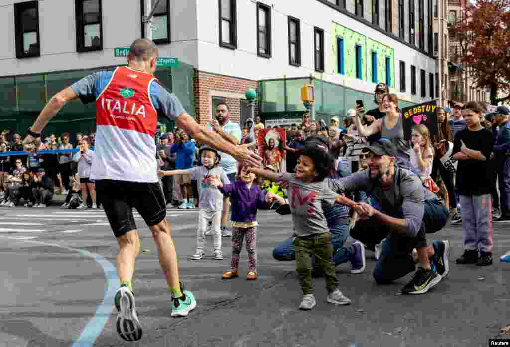 A runner high fives spectators during the New York City Marathon.