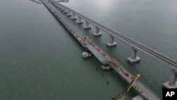 In this handout photo released by the Russian Federal Road Transport Agency (Rosavtodor) on Nov. 8, 2022, workers repair the side of damaged spans of the road section of the Crimean Bridge connecting Russian mainland and Crimean peninsula.