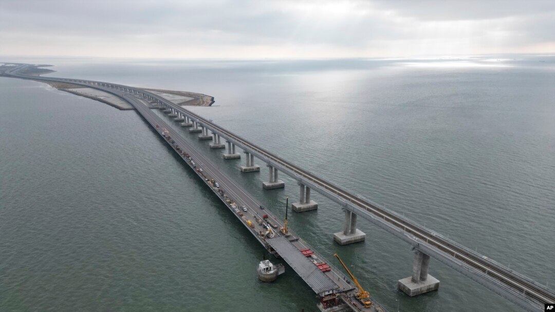 In this handout photo released by the Russian Federal Road Transport Agency (Rosavtodor) on Nov. 8, 2022, workers repair the side of damaged spans of the road section of the Crimean Bridge connecting Russian mainland and Crimean peninsula.