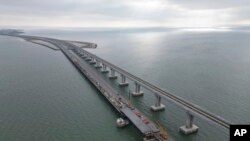 In this handout photo released by the Russian Federal Road Transport Agency (Rosavtodor) on Nov. 8, 2022, workers repair the side of damaged spans of the road section of the Crimean Bridge connecting Russian mainland and Crimean peninsula.