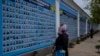 A woman stands in front of the "Memory wall of fallen defenders of Ukraine in Russia-Ukranian war" in downtown Kyiv, Ukraine, Nov. 7, 2022.