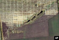 This Oct. 14, 2022, satellite photo from Planet Labs PBC shows an area of recently dug graves in a cemetery just northwest of Mariupol, Ukraine.