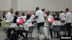 Punonjësit zgjedhorë duke përpunuar fletët e votimit me postë në Detroit, Miçigan (8 nëntor 2022)