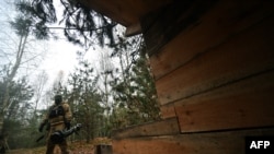 A Ukrainian border guard carries an Anglo-Swedish NLAW anti-tank missile launcher at a fortified position near the Ukrainian border with Russia and Belarus, Nov. 3, 2022.